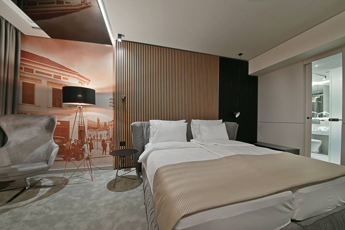 Una habitación de hotel moderna con una cama grande, un escritorio y una televisión.