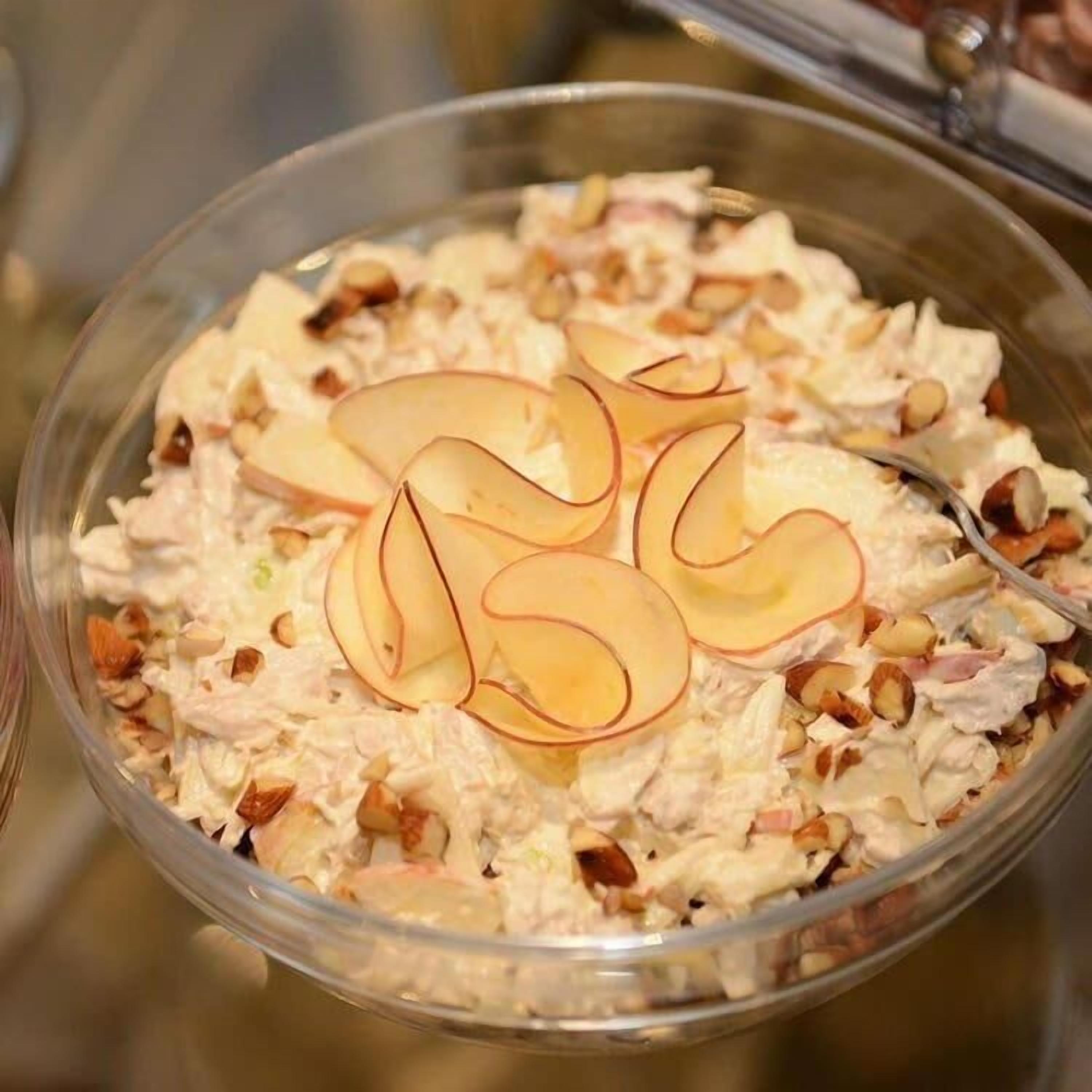 A bowl of salad with sliced apples and nuts.