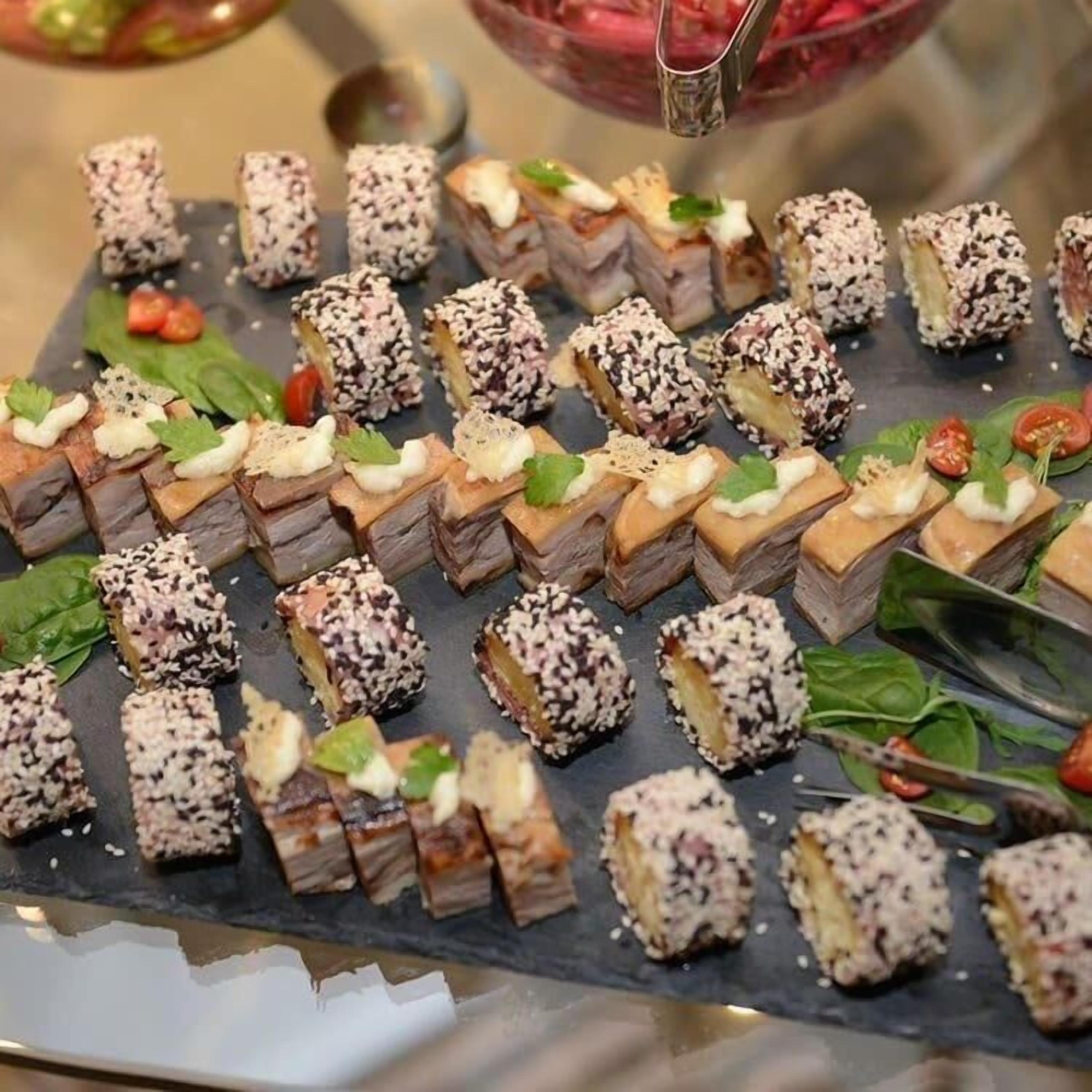 Un buffet proposant une variété de plats, notamment des sushis et des plats de viande, présentés sur une planche en ardoise.