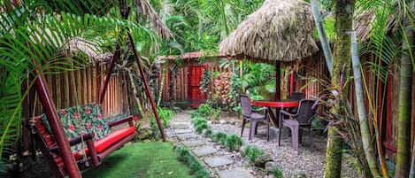Un jardin tropical doté d’une structure à toit de chaume, d’un sentier en pierre et d’un espace de détente extérieur.