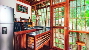 A kitchen with wooden cabinets, a stainless steel refrigerator, a sink, and a stove. - Charming 2-person Apartment in Playa Chiquita, Puerto Viejo (Cahuita)