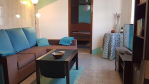 A cozy living room with a brown sofa, a small table with a bowl, and a TV on a stand. - Pet- and biker-friendly vacation apartment with terrace in a quiet location (Regalheiras de Lavos)