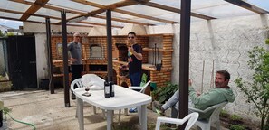 An outdoor patio area with a brick oven, a table with bottles, and a chair. - Pet- and motorcyclist-friendly vacation apartment with a terrace in a quiet location (Regalheiras de Lavos)