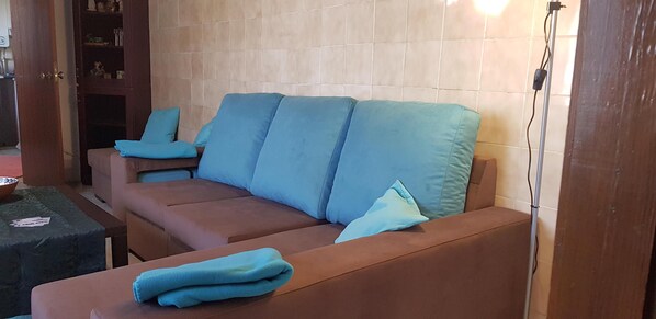 A living room with a brown sofa and blue cushions, a wooden cabinet with glass doors, and a small table with a bowl. - Pet- and motorcyclist-friendly vacation apartment with a terrace in a quiet location (Regalheiras de Lavos)