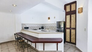 A compact kitchen with a central island, a dining area with chairs, and a refrigerator. - Hotel Suites Ixtapa Plaza (Ixtapa)