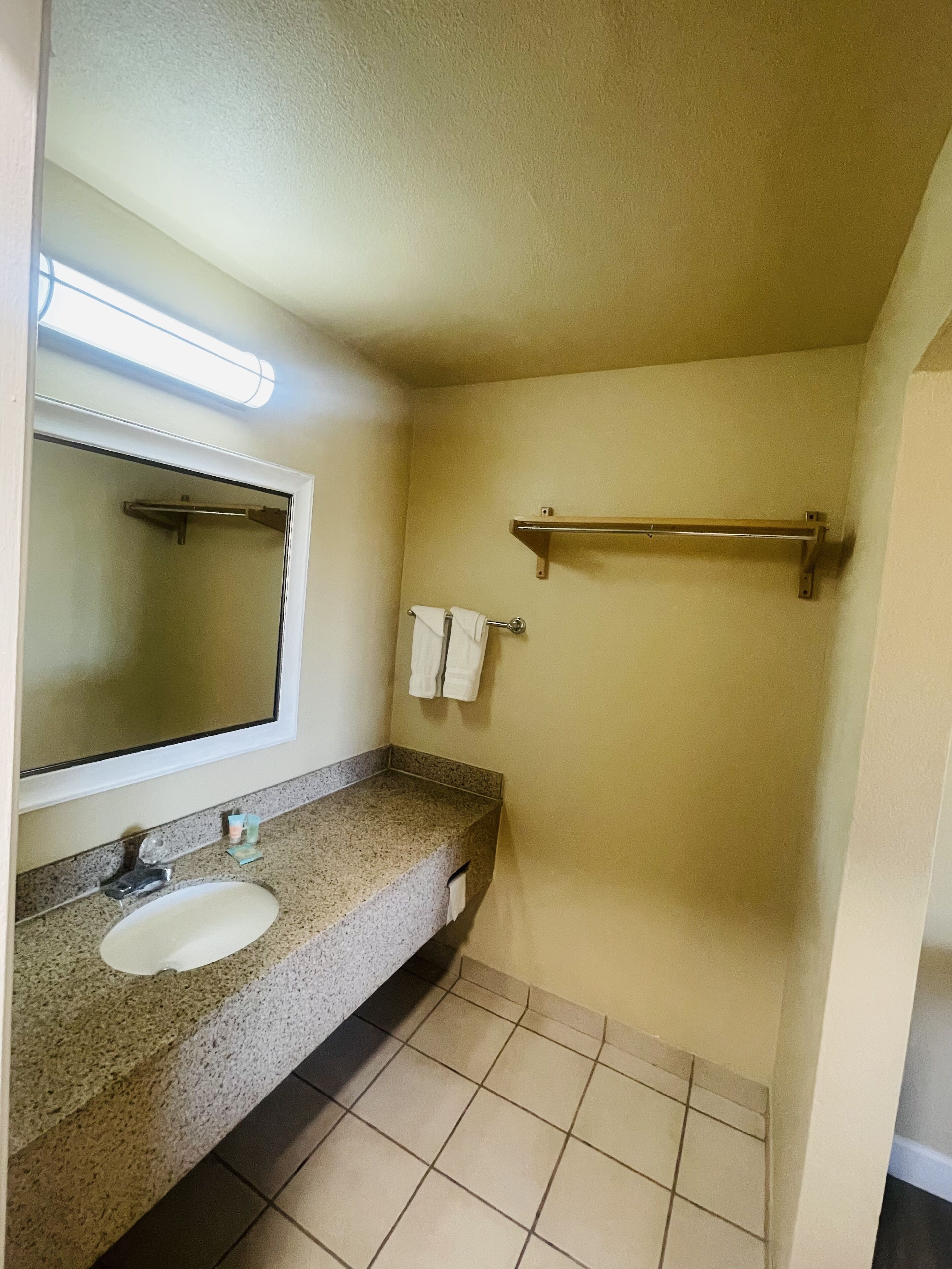 A bathroom with a sink, mirror, towel rack, and a shower area.