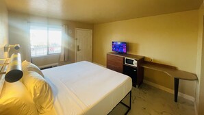 A hotel room with a bed, a TV on a wooden dresser, a window with a view of the outside, and a door. - Happy Smart Inn I-10 Eloy and Casa Grande (Eloy)