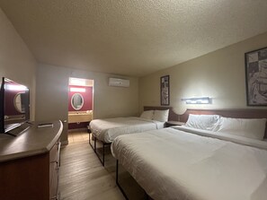 A hotel room with two beds, a desk, a mirror, a TV, and a wall-mounted air conditioner. - Happy Smart Inn I-10 Eloy and Casa Grande (Eloy)