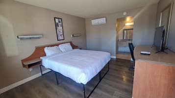 Une chambre d’hôtel avec un lit, un bureau, une télévision et une salle de bain que l’on aperçoit à l’arrière-plan.