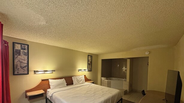 A hotel room with a bed, bedside tables, a TV, a bathroom with a bathtub, and a shower. - Happy Smart Inn I-10 Eloy and Casa Grande (Eloy)