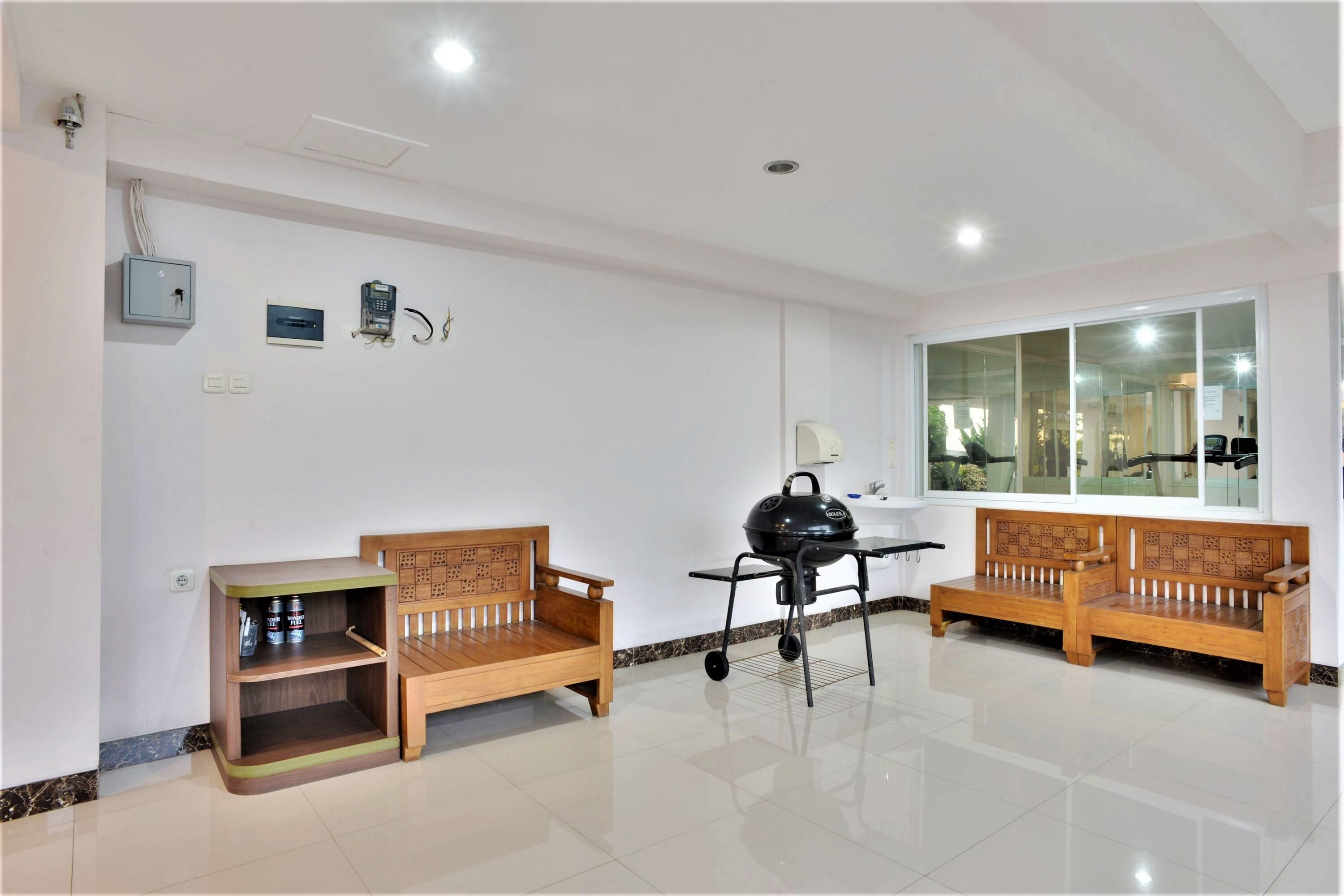 A clean, well-lit room with two wooden benches, a small table, a grill, and a window with a view.