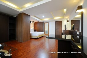 Eine luxuriöse Penthouse-Wohnung mit zwei Schlafzimmern, Holzböden, einem großen Bett, einem Schminktisch mit Spiegel und Einbauschränken.