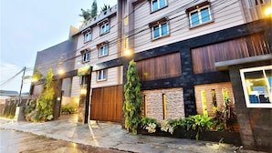A multi-story building with a modern design, featuring a combination of brick and wood paneling, large windows, and a well-maintained exterior with greenery. - Kasira Residence Serviced Apartment (South Tangerang)