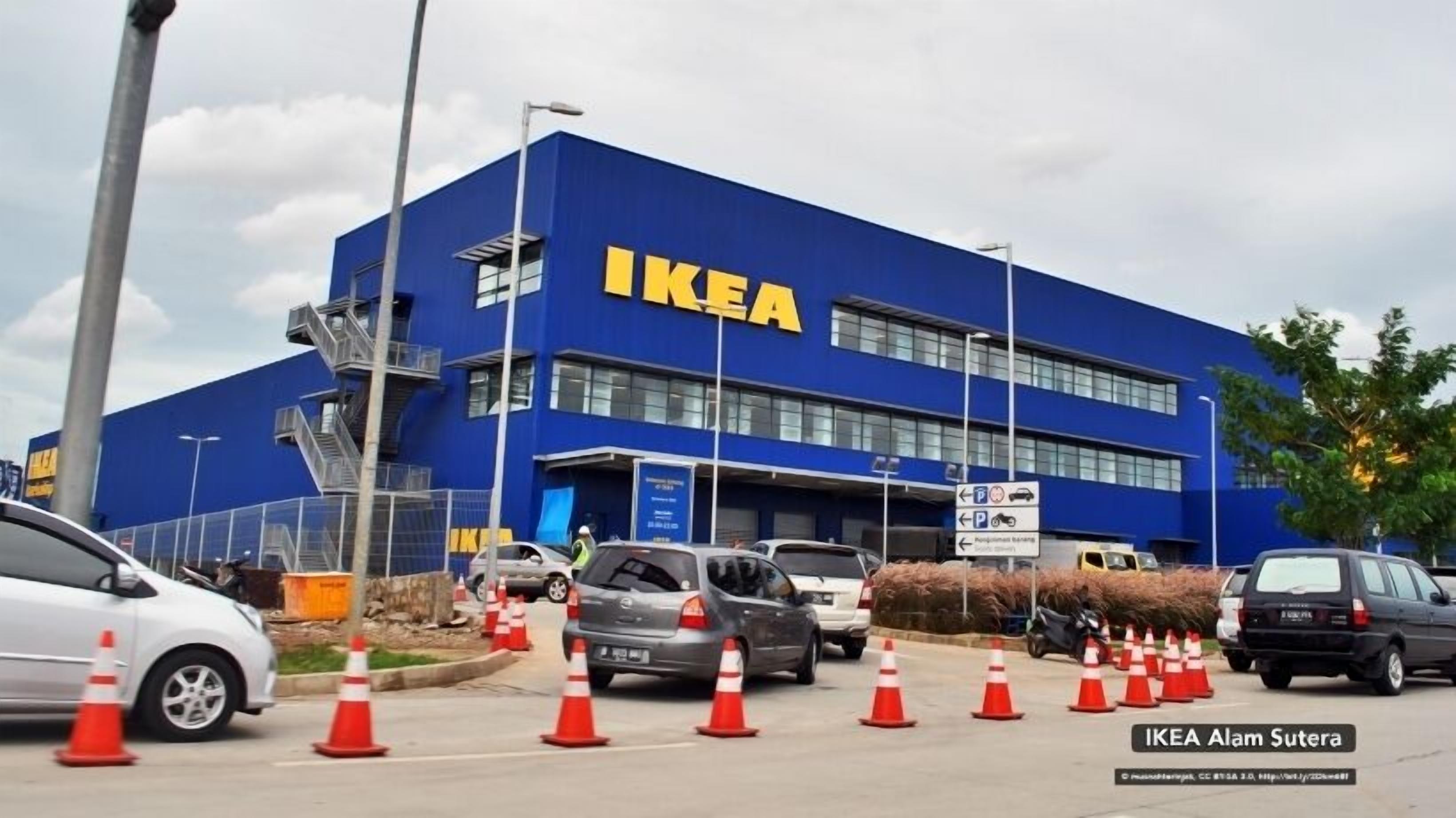 A blue IKEA store with multiple cars parked in front and traffic cones indicating construction or maintenance work.