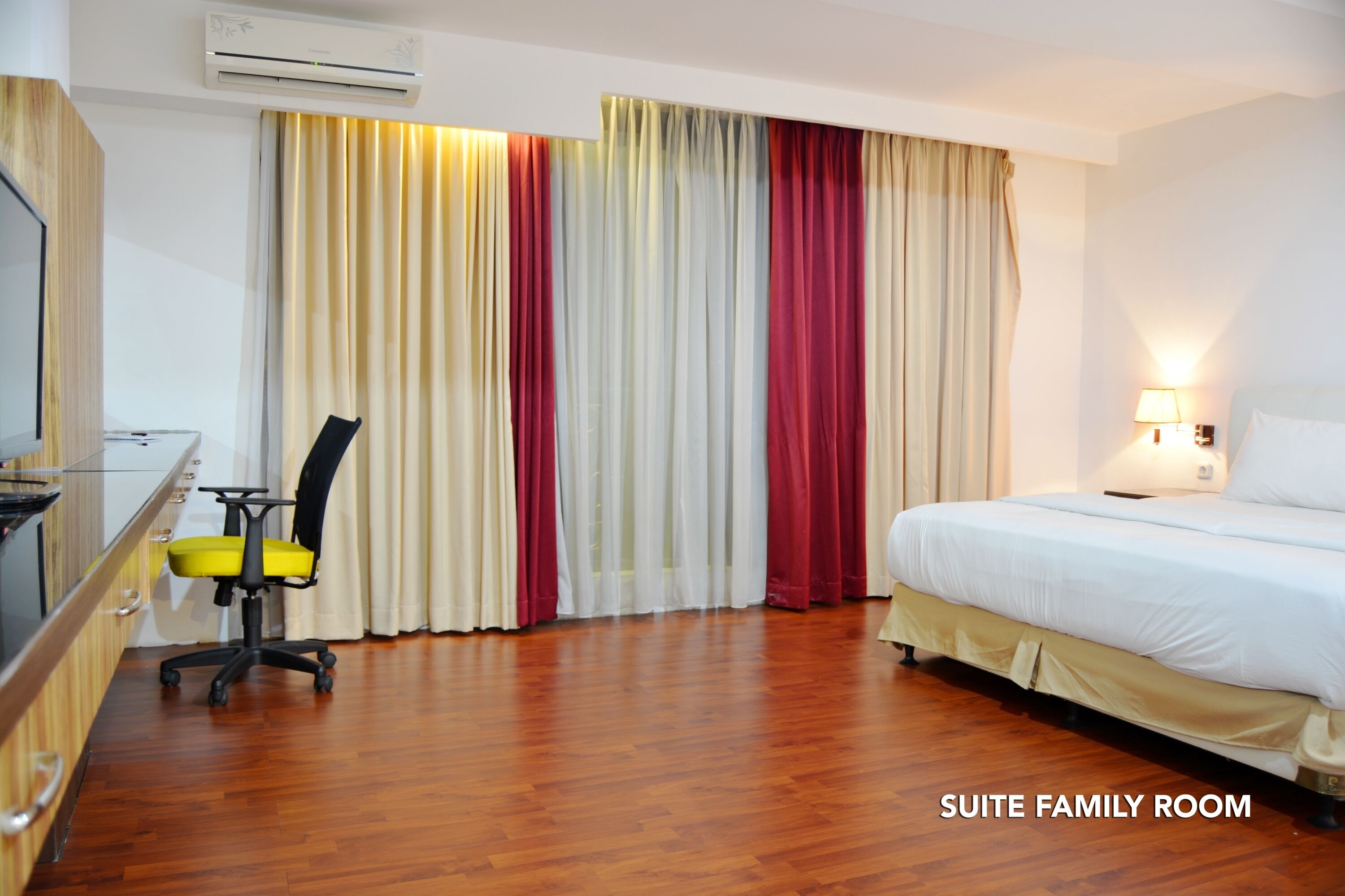 A suite family room with a bed, a desk with a chair, and a TV.