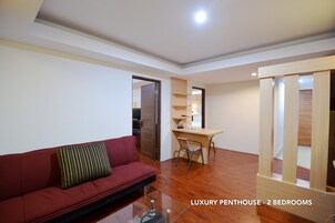 Ein luxuriöses Penthouse mit zwei Schlafzimmern, einem roten Sofa, einem Holztisch und einem Glastisch.