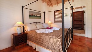 A four-poster bed with a patterned bedspread, two bedside lamps, a nightstand, and a painting on the wall. - The Carib House 5 Bedrooms And Pool Close To Beach (Falmouth Harbour)