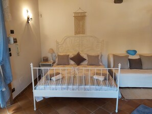 Ein Schlafzimmer mit Bett, Nachttisch, Lampe und Wandleuchte.