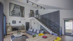 Ein modernes Wohnzimmer mit Treppe, Essbereich und Fernseher.