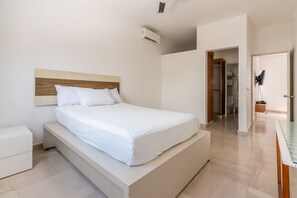 Une chambre à coucher moderne avec un grand lit, une table de chevet, un banc intégré et un appareil de climatisation.