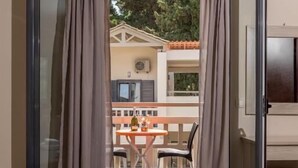 Habitación de hotel con cama, televisión y balcón con mesa y sillas.