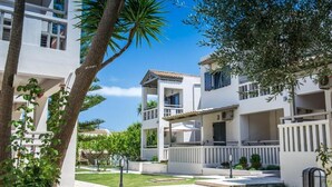 Un complejo residencial moderno con varias edificaciones de dos pisos, césped cuidado y cielo azul despejado.