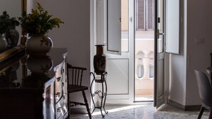 An interior hallway with a wooden dresser, a chair, and a decorative stand with a vase.