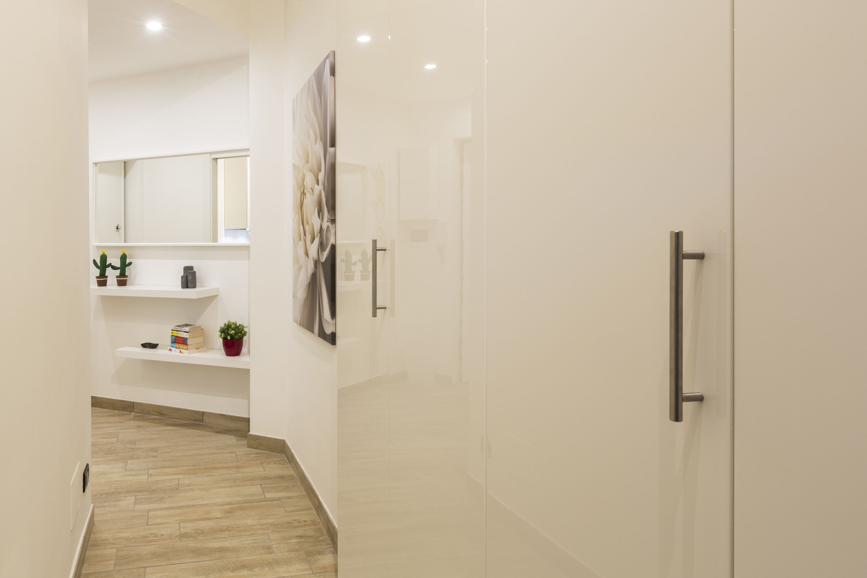 A modern bathroom with a glass shower enclosure, a white sink with a mirror above, and a small shelf with toiletries.