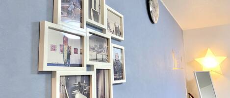 Pared con varias fotos enmarcadas, un reloj y una lámpara con forma de estrella.