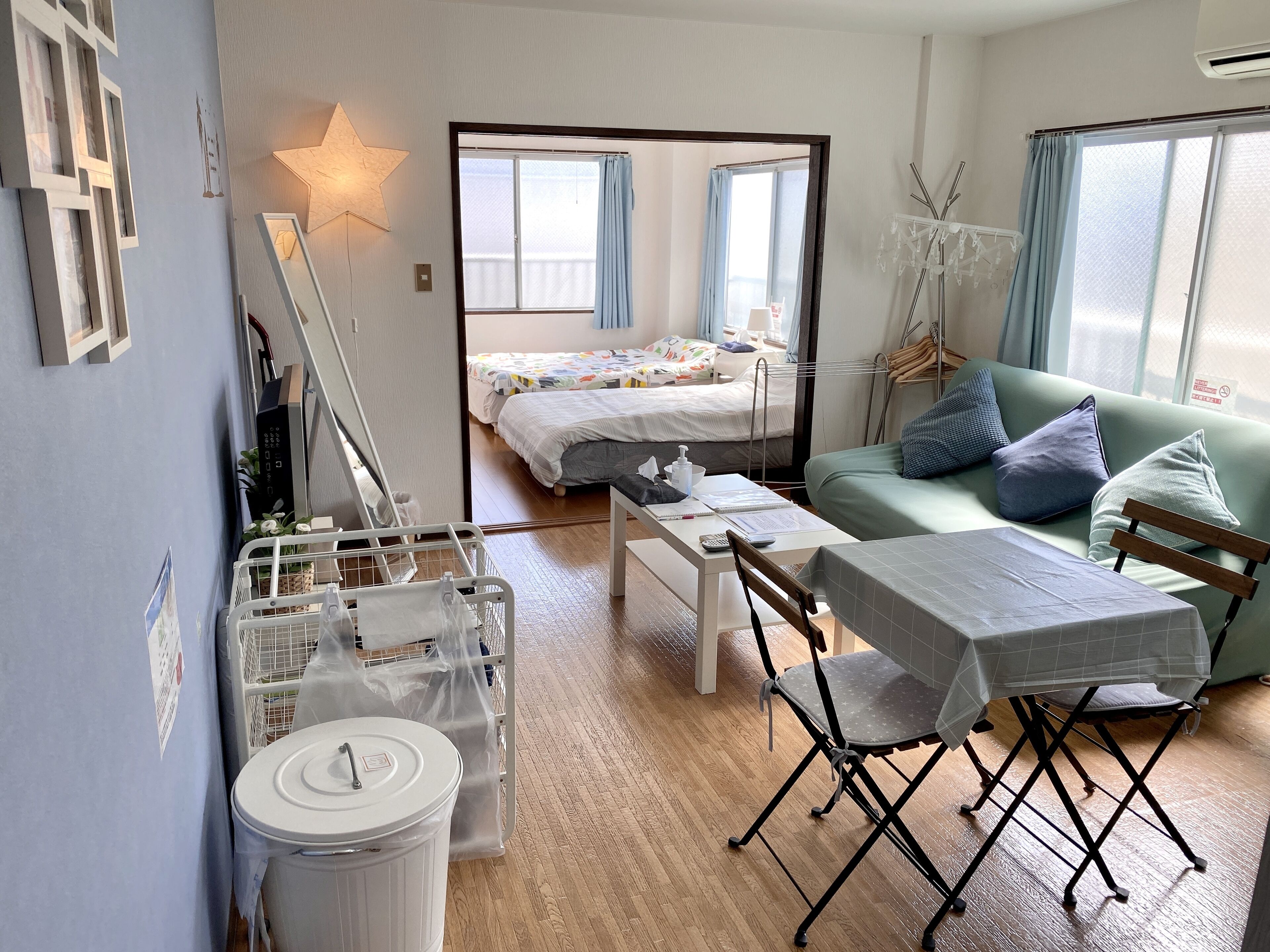 A compact hotel room with a bed, a sofa, a dining table, and a small kitchen area.