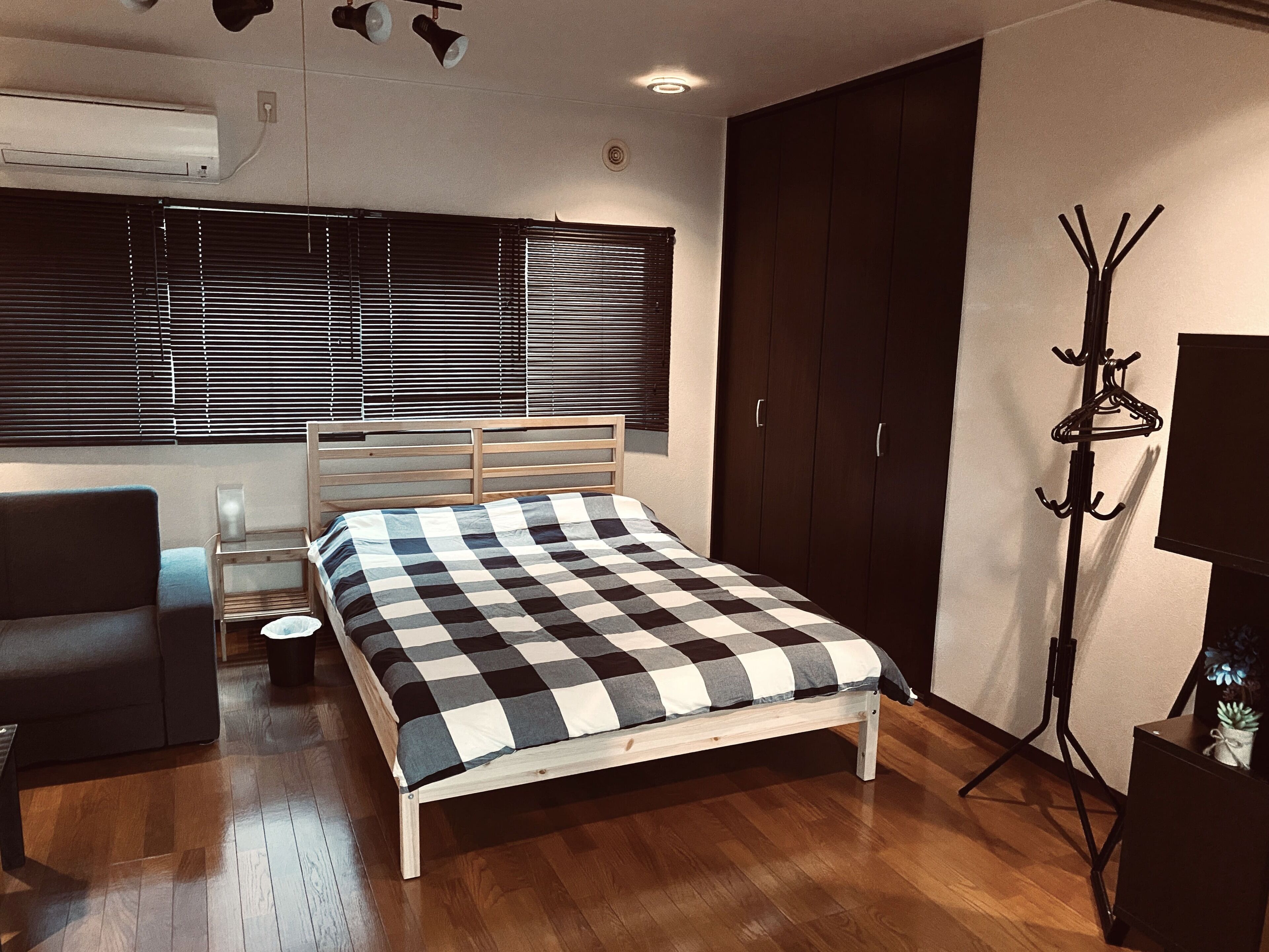 A bedroom with a bed, a chair, a coat rack, and a wardrobe.