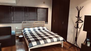 A bedroom with a bed, a chair, a coat rack, and a wardrobe.
