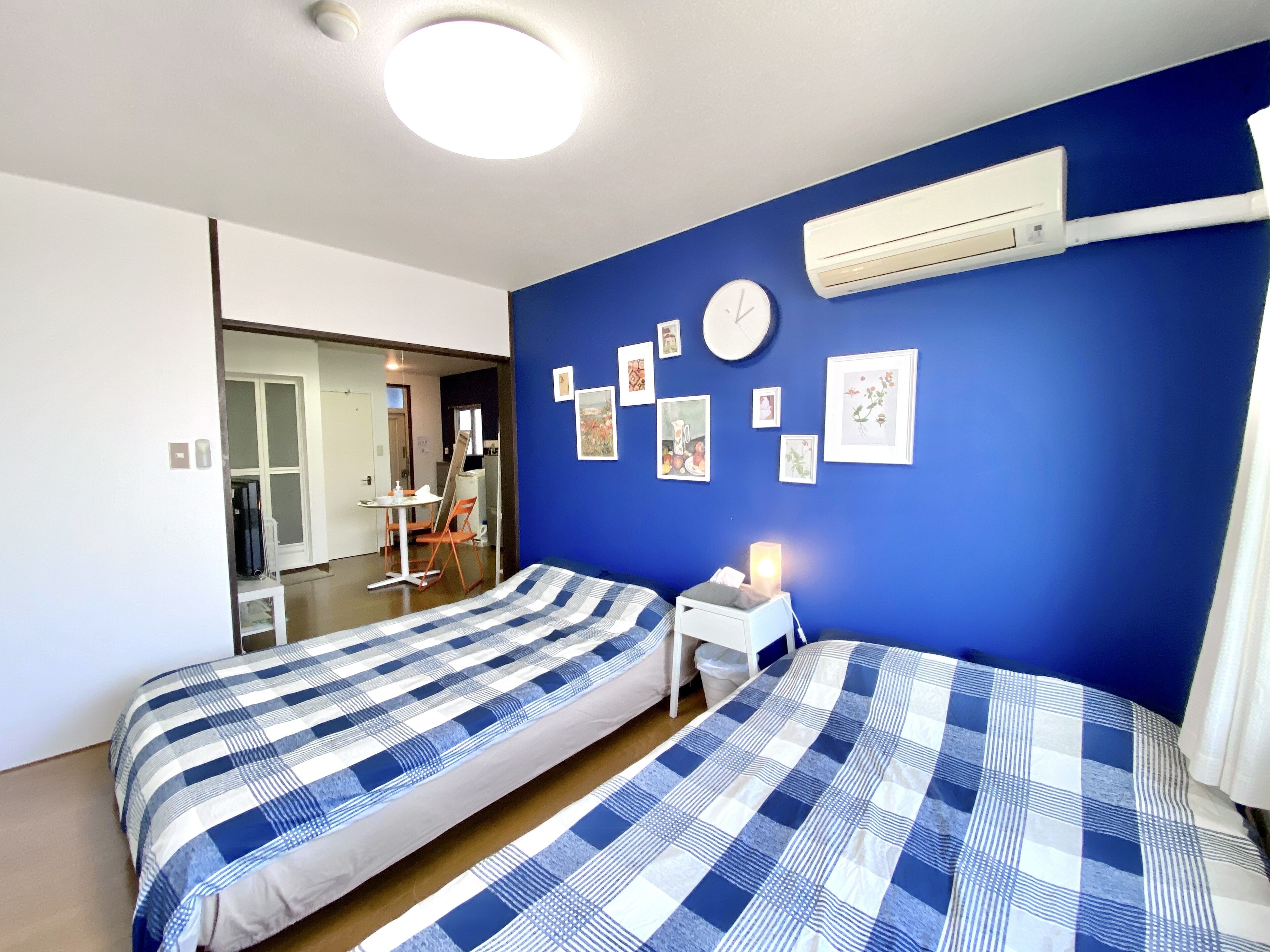 A bedroom with two beds, a desk, and an air conditioning unit on the wall.