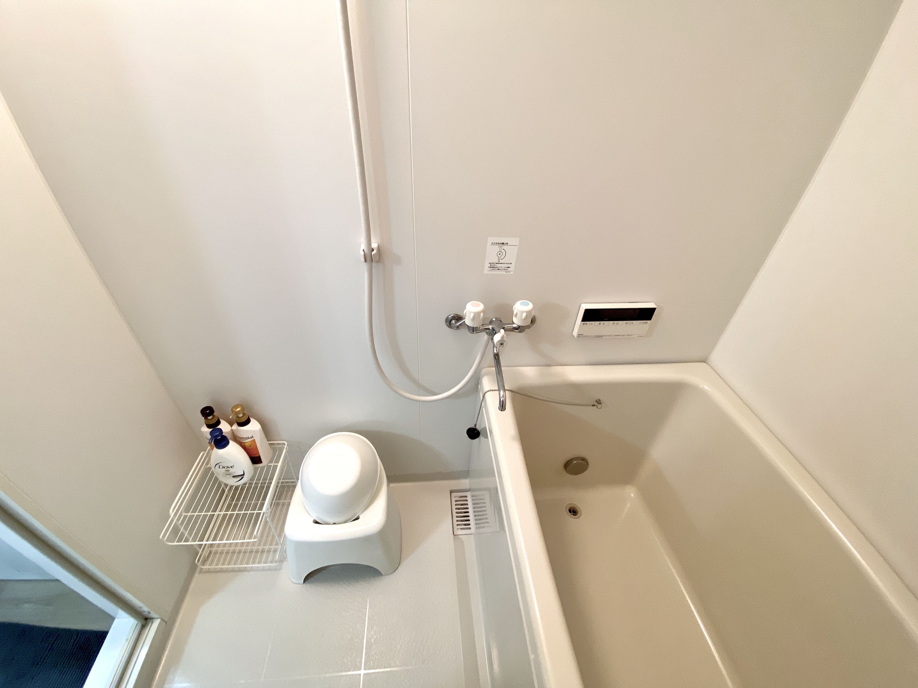 A bathroom with a bathtub, a showerhead, and a hand dryer.
