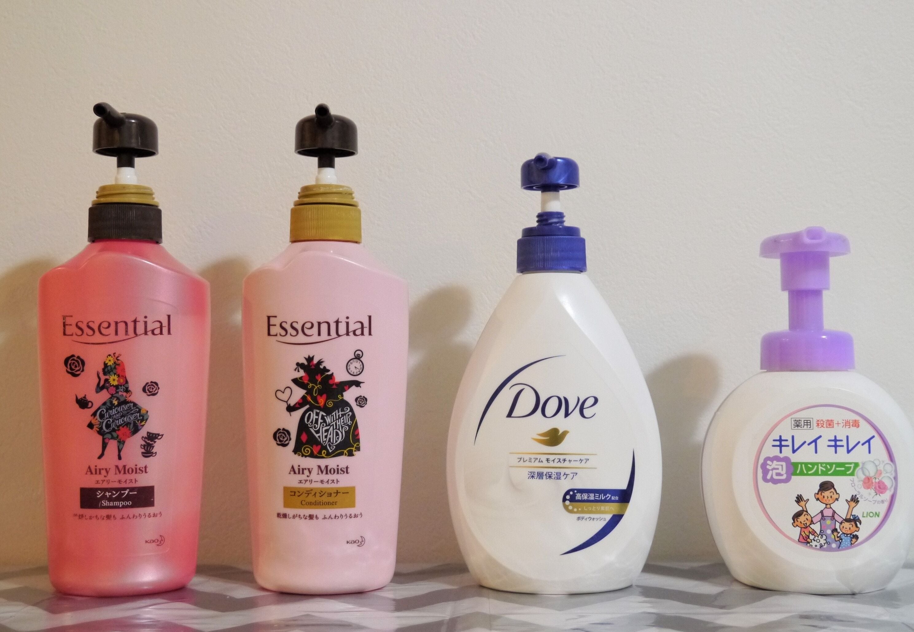Four bottles of shampoo with different brand labels and pump designs.