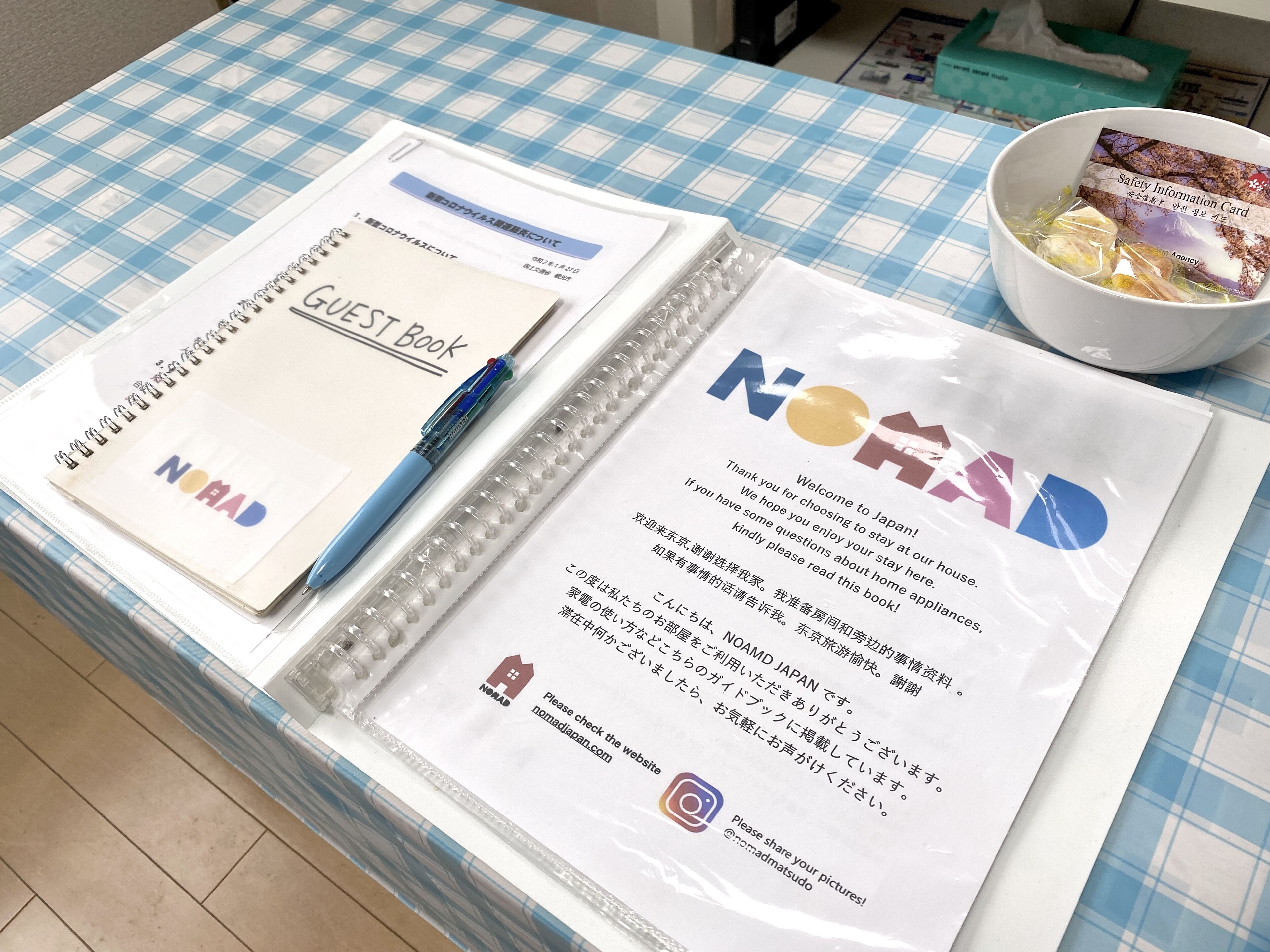 A table with a guest book, a pen, a welcome card, and a bowl of snacks.