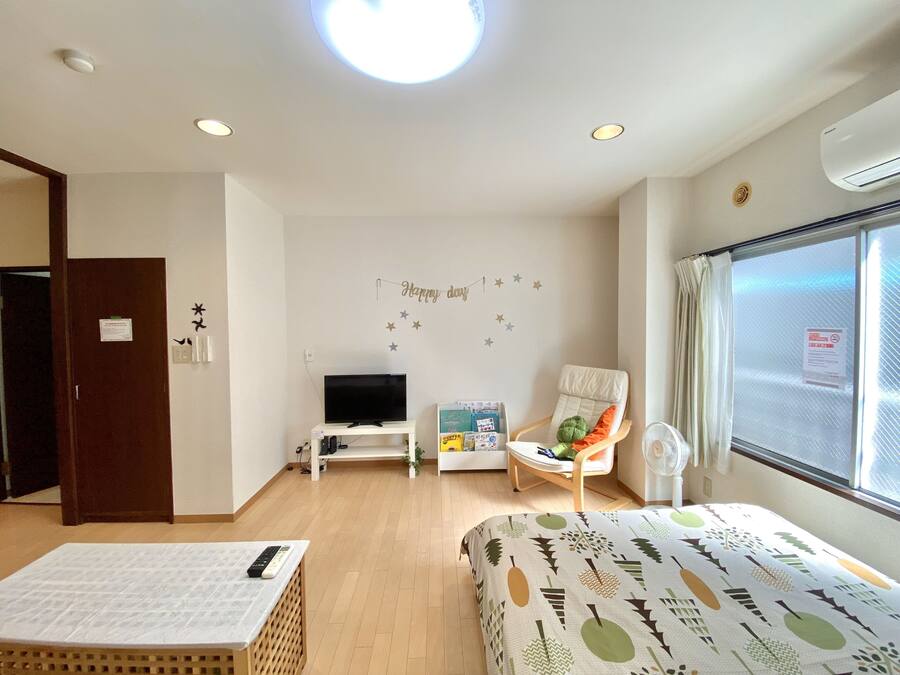 Quarto de hotel com cama, televisão, cadeira, berço e janela com vista.