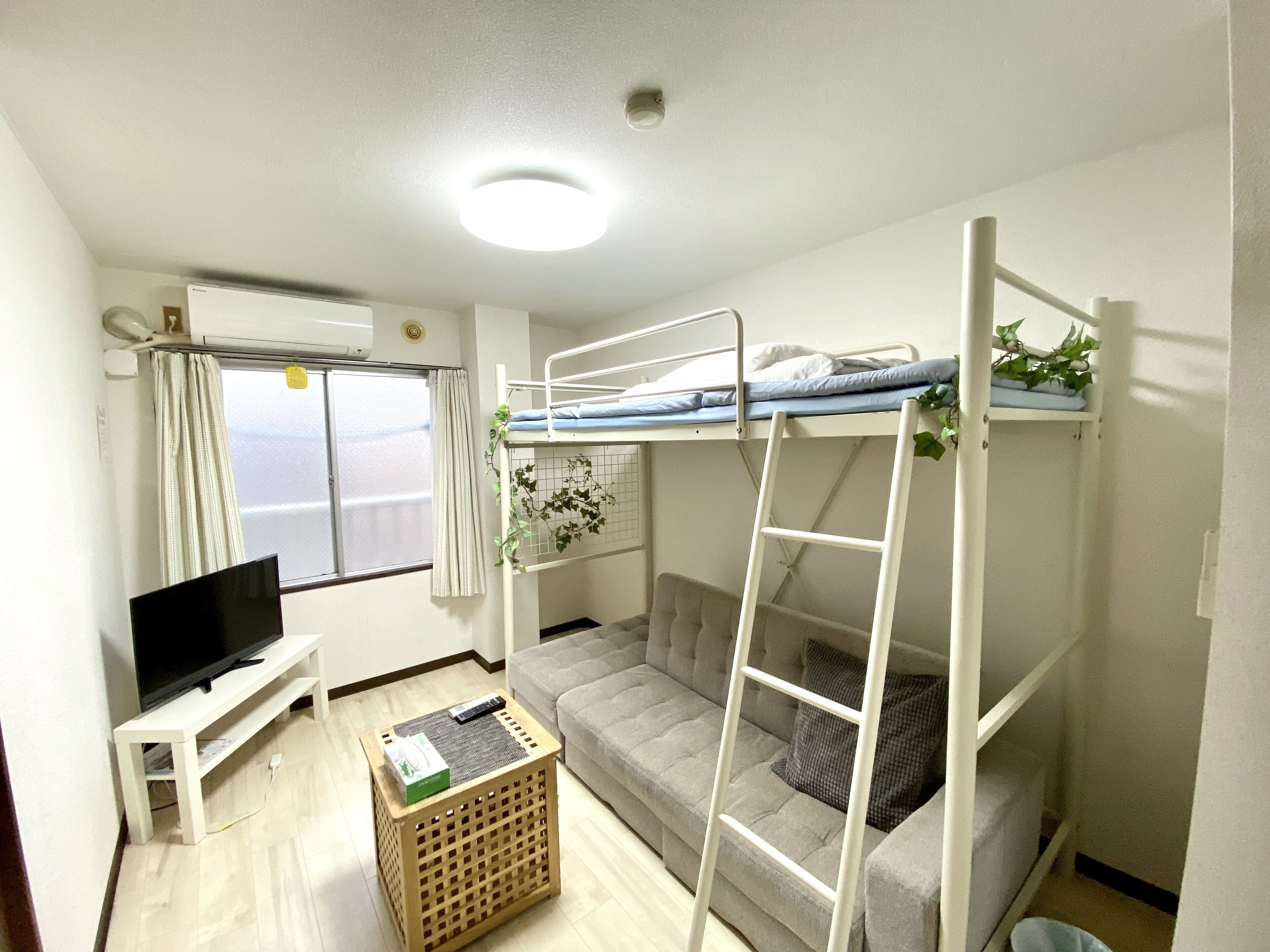 A compact room with bunk beds, a sofa, a TV, and a small table.