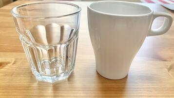 A clear glass and a white ceramic mug on a wooden table.