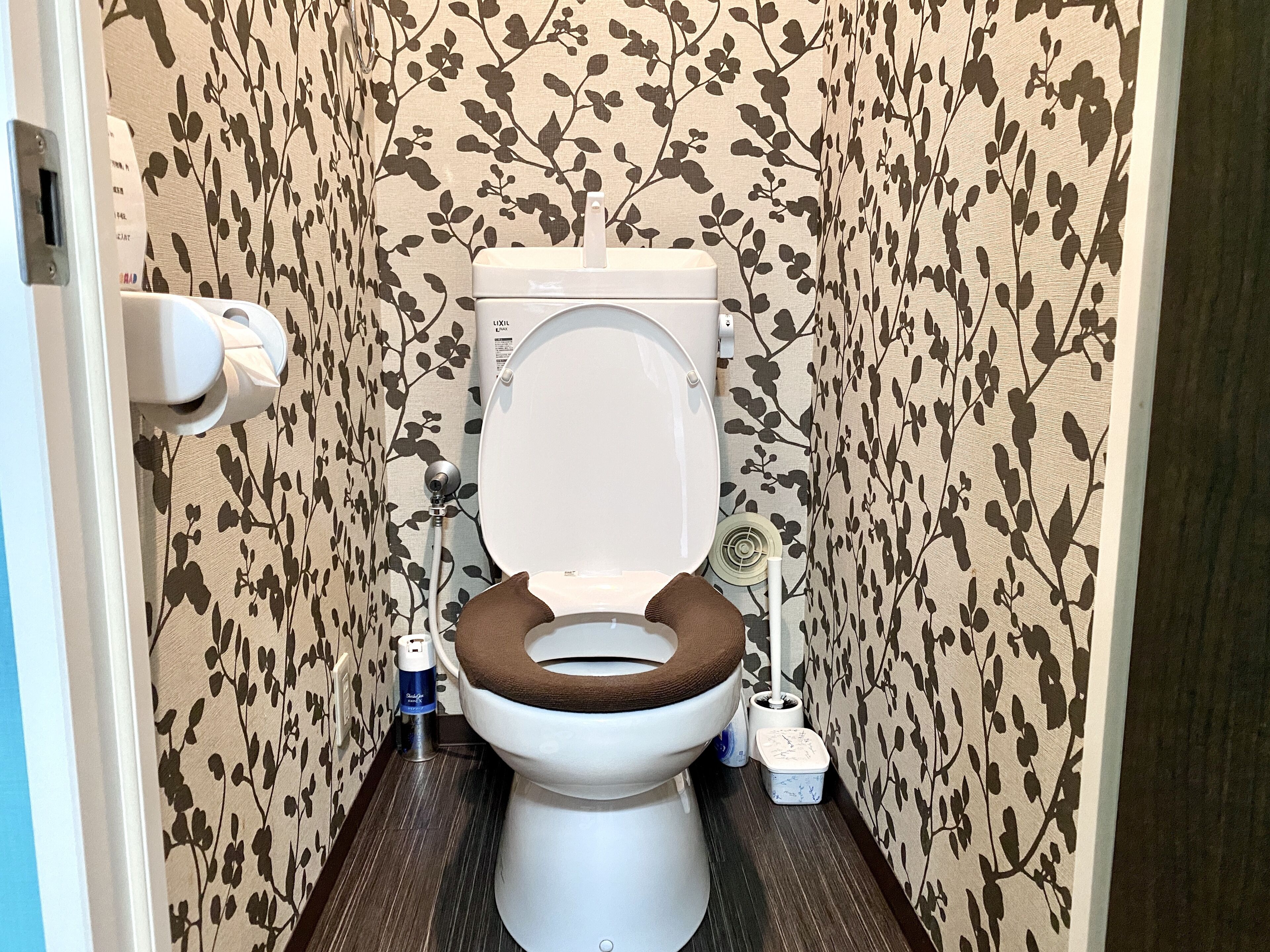 Des toilettes avec un abattant marron, une brosse pour les toilettes et un bidet.