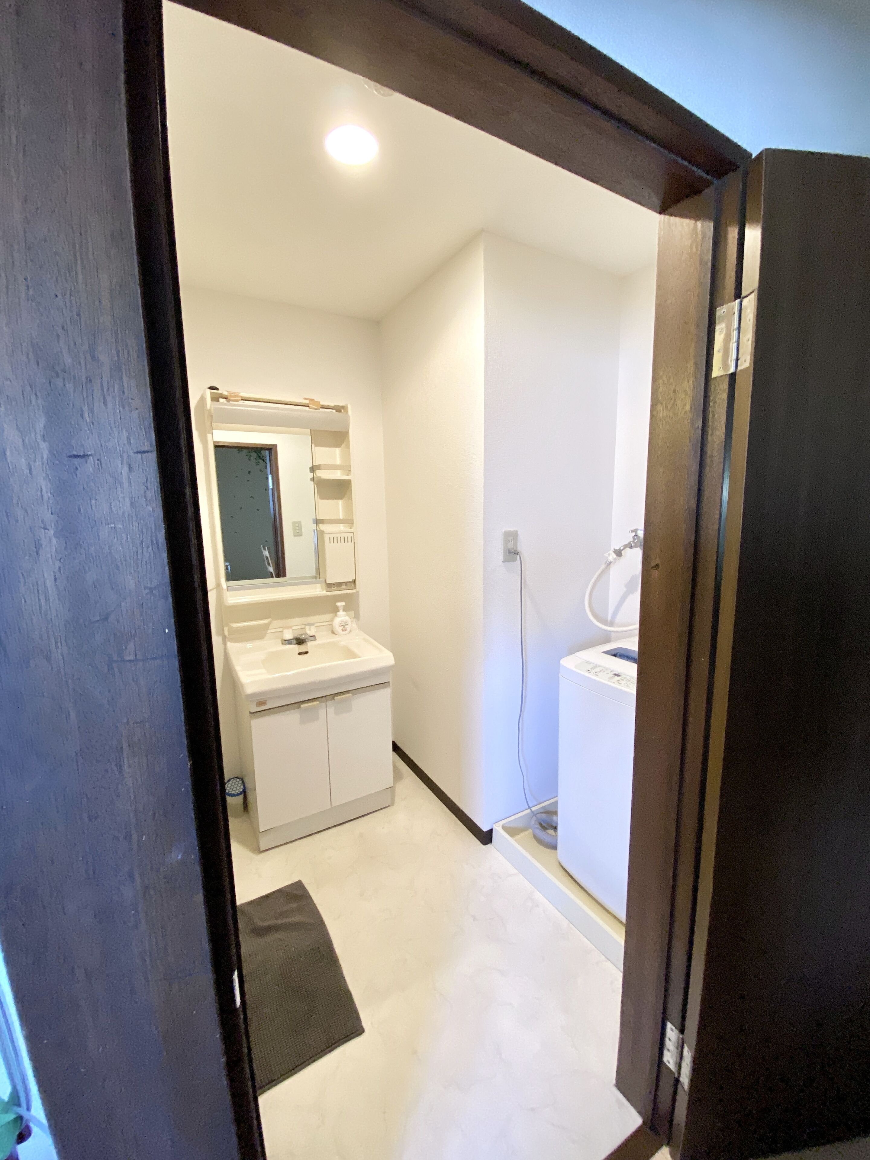Un baño pequeño y limpio con lavamanos, espejo y retrete blancos.