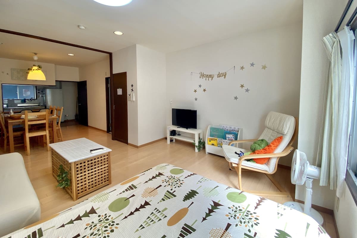 Una sala moderna con un sofá, un televisor, una mesita y una decoración de pared que dice "Happy day".
