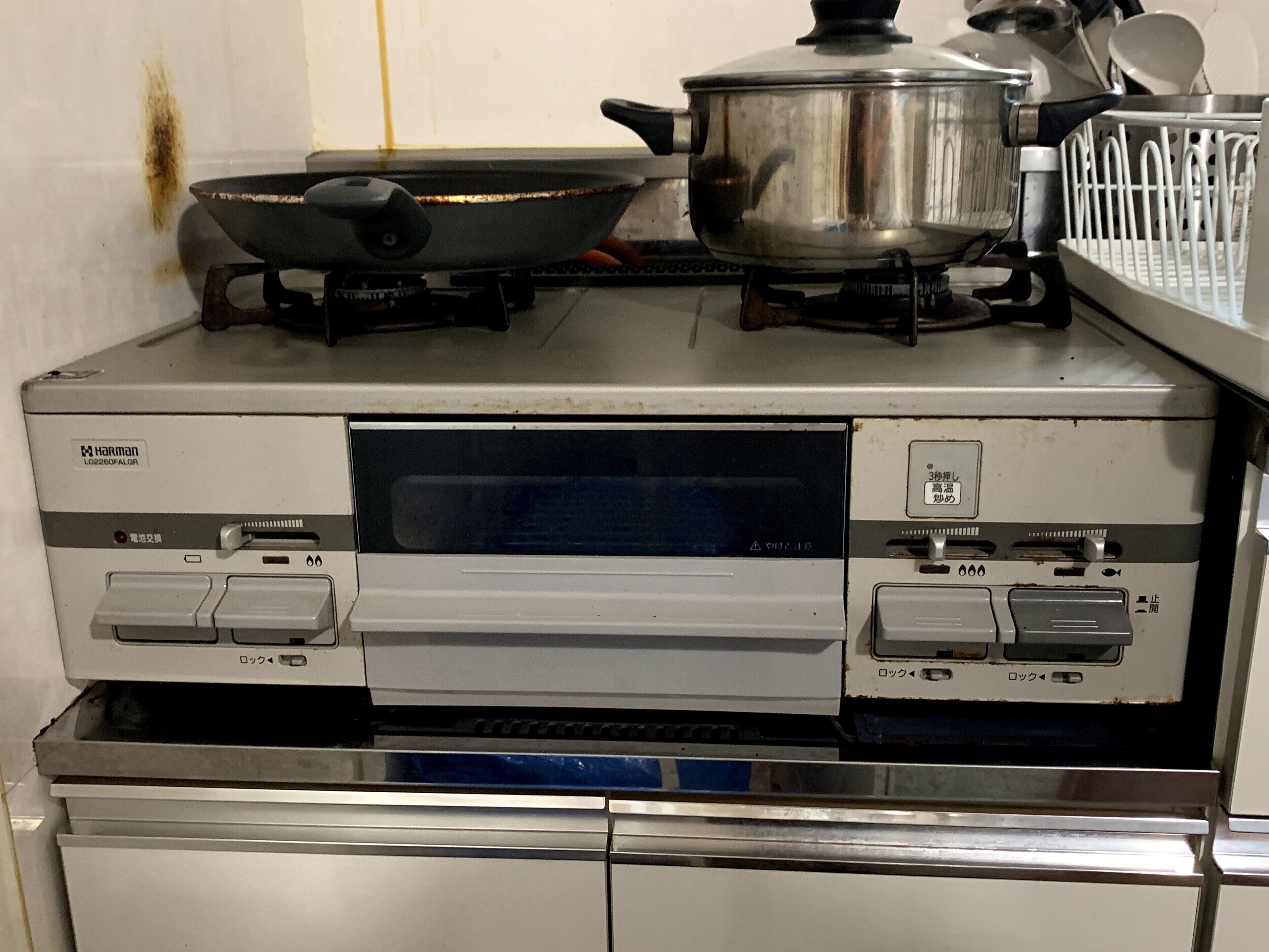A kitchen with a stove, a frying pan, and a pot on top.
