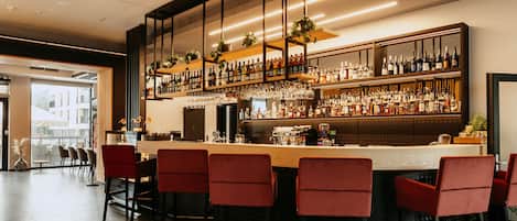 Zona de bar con diversas opciones de asientos y una amplia variedad de licores.