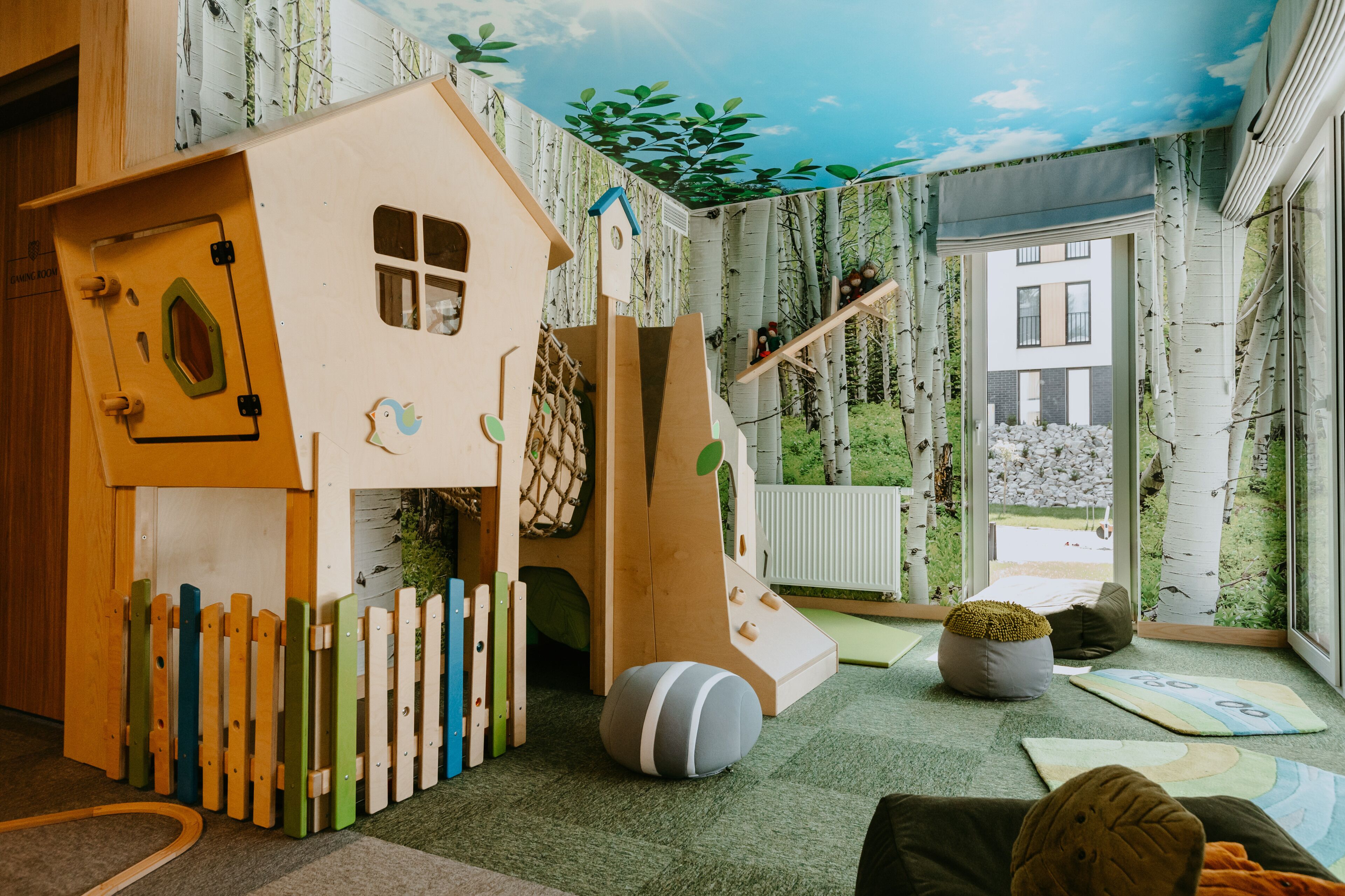A children's play area with a wooden house, slide, and climbing net.