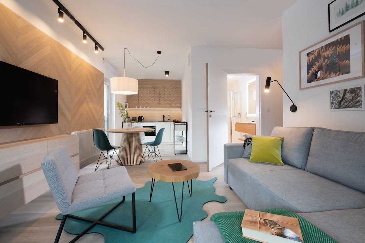 Una sala moderna con un sofá, sillas, una mesa de centro y un televisor.