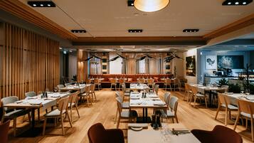 Ein Restaurant mit Holzboden, mehreren Esstischen und einer zentralen Sitzgruppe mit einer niedrigen Bank.