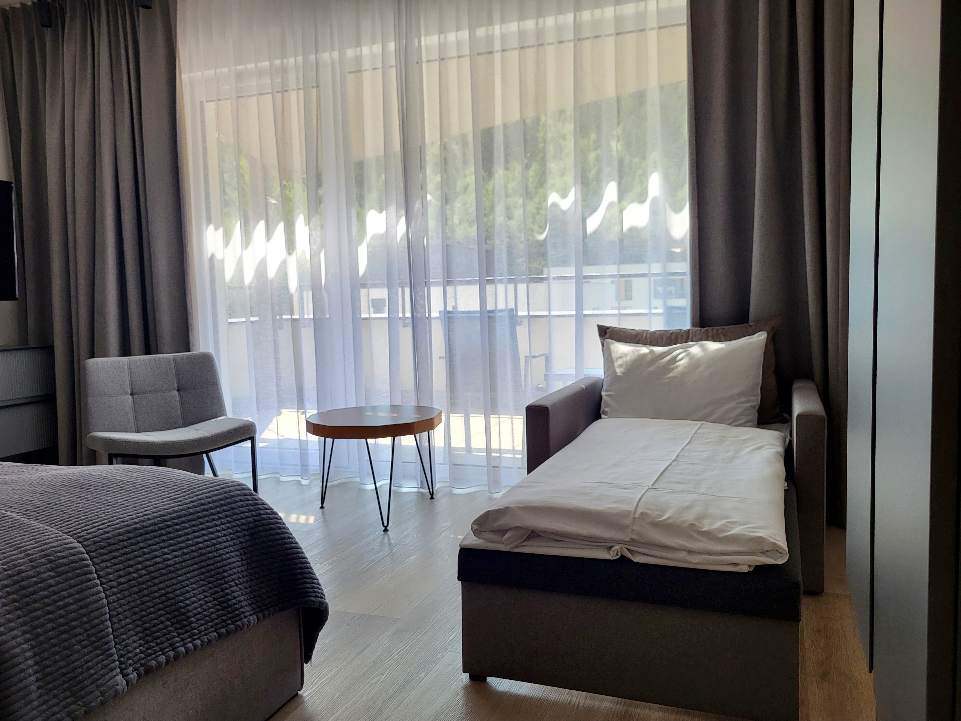A hotel room with a bed, a sofa, a chair, and a small table.