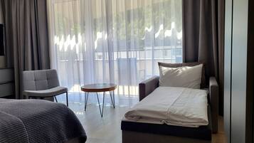 A hotel room with a bed, a sofa, a chair, and a small table.
