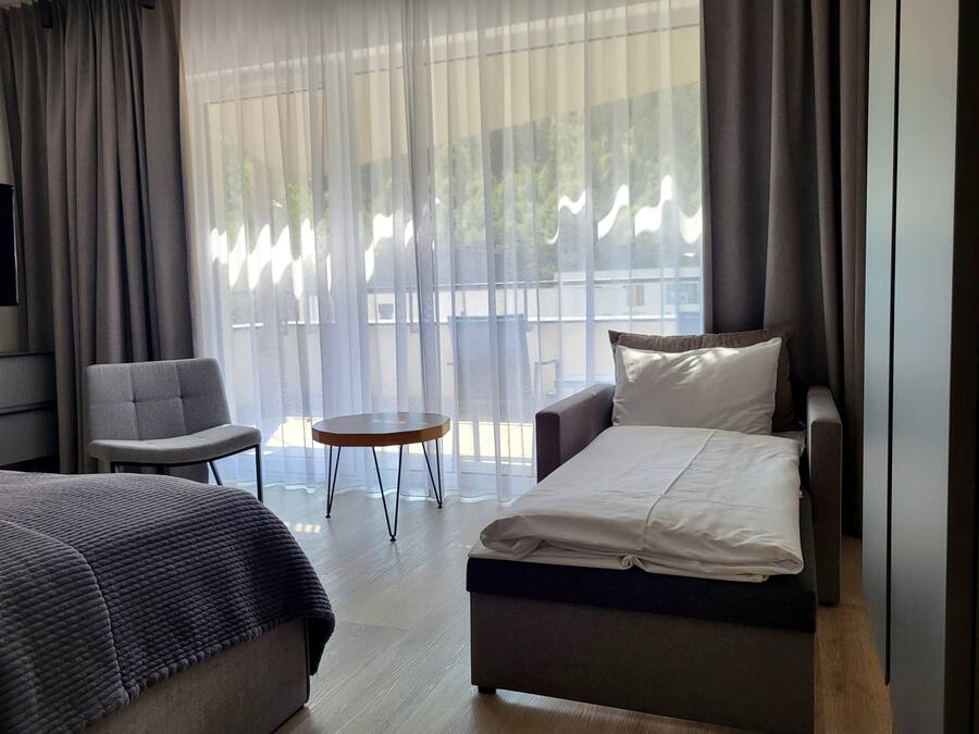 A hotel room with a bed, a sofa, a chair, and a small table.